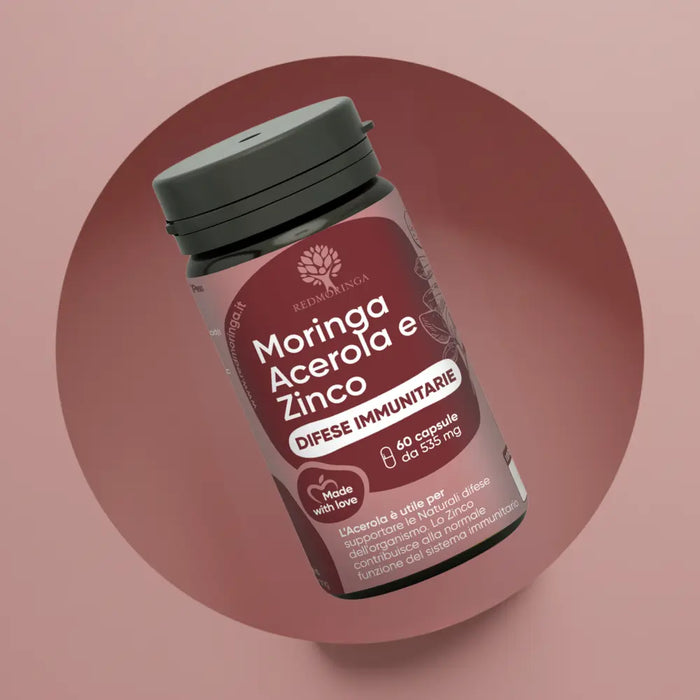 Primo piano del flacone RedMoringa Difese Immunitarie con Moringa, Acerola e Zinco. Confezione da 60 capsule da 535 mg su sfondo circolare bordeaux e rosa.