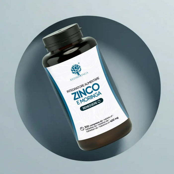 Inquadratura dall'alto del flacone "Integratore Alimentare Zinco e Moringa" di RedMoringa su sfondo grigio e azzurro. La confezione contiene 300 compresse da 400 mg.